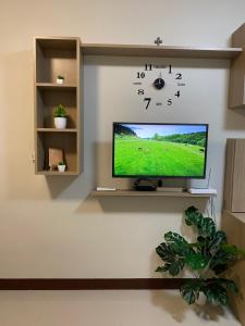 a tv on a wall with a clock on it at ARC Hive Staycation in Suba