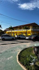 a parking lot with cars parked in front of a yellow building at Condomínio Diver in Vera Cruz de Itaparica +4 photos