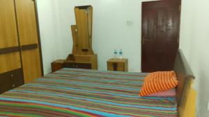 a bedroom with a bed with an orange pillow on it at Ranga's house in Minuwangoda