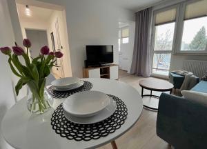 a living room with a table with plates and flowers on it at Apartament Jedenastka in Kraśnik