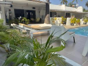 a patio with a white chair and a pool at Maison Mimosa in Grand-Bassam