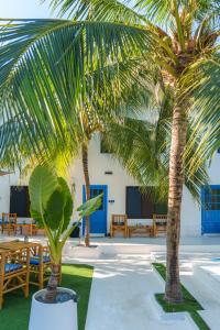 two palm trees in a courtyard with tables and benches at Lanta Secret House in Ko Lanta
