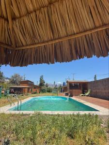a swimming pool under a thatched roof at Cabaña Camino al Valle in La Marquesa