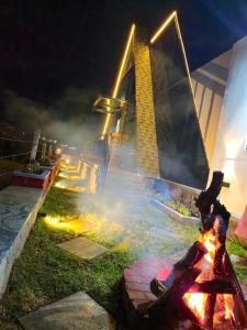 a person is sitting around a fire pit at night at SkyGrove in Kodaikānāl