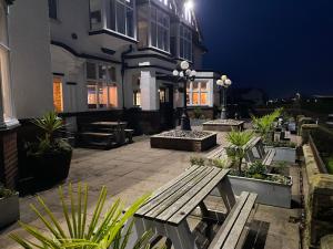 a patio with a wooden bench in front of a building at King Alfred Hotel in Barrow in Furness