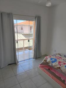a bedroom with a bed and a large sliding glass door at Casa Confort Praia dos Ingleses in Florianópolis