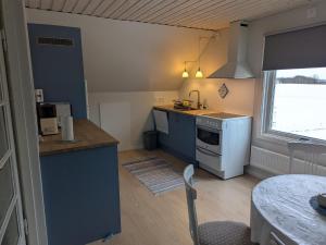 a kitchen with blue cabinets and a white stove top oven at Vindslägenhet på Bjäre in Båstad
