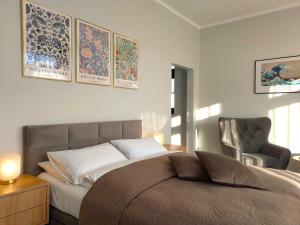 a bedroom with a bed and a chair and pictures on the wall at Tullu Apartament - w centrum, blisko bulwaru, blisko molo in Ostróda +19 photos