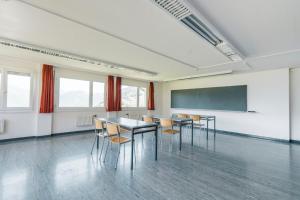 a class room with tables and chairs and a chalkboard at Schwendihaus in Amden
