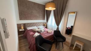 a bedroom with a bed and two chairs and a mirror at La Divina Commedia in Florence