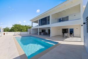 a villa with a swimming pool in front of a house at Lagun Ocean View Apartments & Studio in Lagun