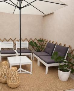 a patio with two benches and a table and an umbrella at Maison De Ruelle in Barletta