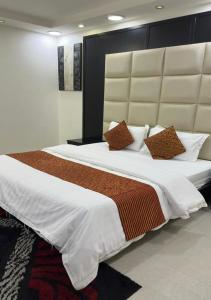a large bed with white sheets and brown pillows at هبوب الغيوم للشقق المخدومة - إقتصادي - Hobob Alghyoum For Serviced Apartments - Economy in Najran +10 photos