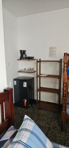 a room with a bed and a table and a shelf at Suíte Trilha do Sol 2 in Arraial do Cabo