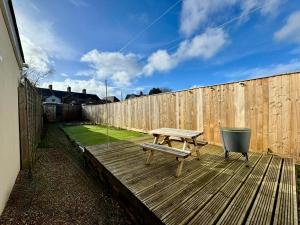 a wooden deck with a bench and a fence at Stylish 2-Bed Home with Garden in Saint Thomas Station