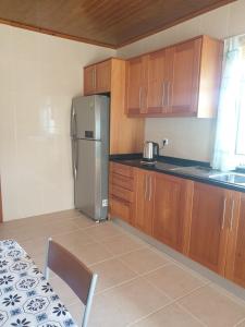 a kitchen with wooden cabinets and a stainless steel refrigerator at Farol Golfe in Ponta do Pargo