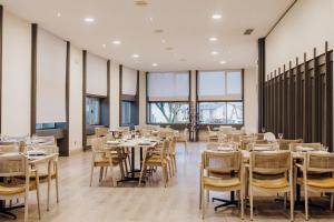 a dining room with tables and chairs and windows at Hotel Vejo in Reinosa