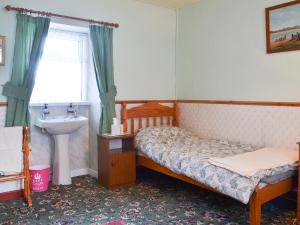 a small bedroom with a bed and a sink at Tanpencefn Mawr in Brynsiencyn +4 photos