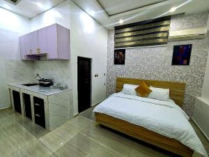 a bedroom with a large bed and a kitchen at Frenezia Hotel and Apartment Ikeja GRA in Ikeja