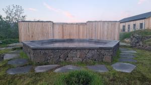 a stone pool in a yard next to a wooden fence at Miðhraun - Lava resort & Restaurant in Midhraun