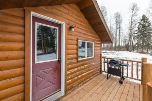 a cabin with a red door and a grill on a deck at The Sheep Camp cabin- Bear Creek Cabins in Winfield