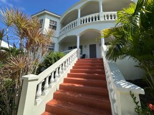 a staircase leading to a white house with palm trees at Krysta's Hideaway in Basseterre