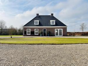 a house with a black roof and a gravel driveway at Het Koetshuis in Zwolle