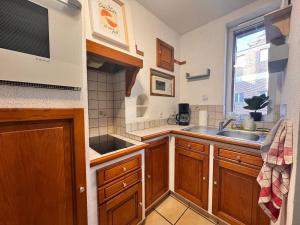 a kitchen with wooden cabinets and a sink and a window at L'écrin de Cambrai - Appt 40 m² centre Cambrai in Cambrai