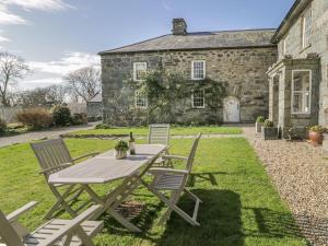 a picnic table and chairs in front of a stone house at Bwthyn Mawr in Harlech