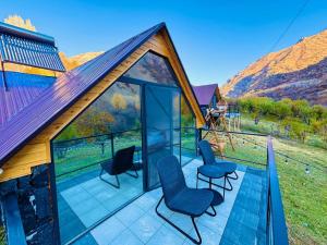 a house with glass doors and chairs on a balcony at Montis Resort in Yeghegis