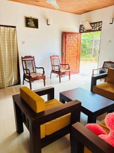 a living room with several chairs and tables at Nihal Villa in Weligama