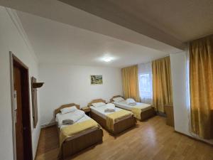 a room with three beds and a window at Pensiune Supca in Râmnicu Vâlcea