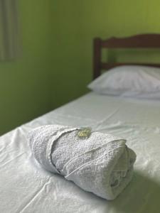 a white towel sitting on top of a bed at Hostel Costa Rio in Rio das Ostras