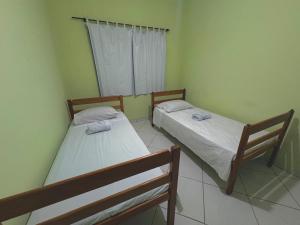 two beds in a room with green walls at Hostel Costa Rio in Rio das Ostras +3 photos