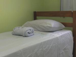 a towel sitting on top of a bed with two pillows at Hostel Costa Rio in Rio das Ostras