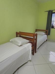two beds in a room with green walls at Hostel Costa Rio in Rio das Ostras