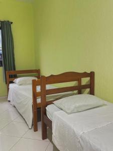 two beds in a room with green walls at Hostel Costa Rio in Rio das Ostras
