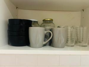 a shelf with cups and glass jars on it at Modern & cozy 2 bedroom flat in Dundee