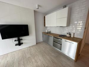 a kitchen with white cabinets and a flat screen tv at ABCD Apartments Centrum in Biała Podlaska