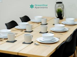 a wooden table with white cups and saucers on it at GreenStar Apartments - Short Walk Away Into Dundee City Centre - 6 Individual Properties from 1 to 3 Bedrooms - Short & Long Stay Offers! in Dundee