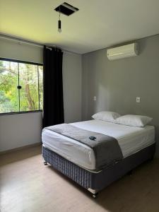 a bedroom with a bed and a large window at Recanto Rivière in Guarapuava +38 photos