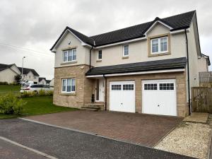a house with two garage doors on a driveway at Luxury 4BR Detached Exec Home in Cadzow
