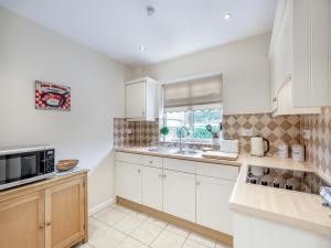 a kitchen with white cabinets and a microwave at Polly's Fold in Grassington