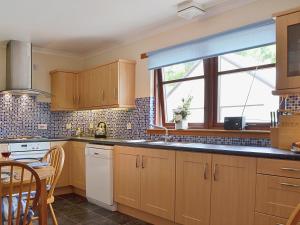 a kitchen with wooden cabinets and a large window at Bethany Cottage in Aberfoyle +12 photos
