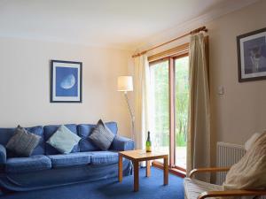 a living room with a blue couch and a table at Bethany Cottage in Aberfoyle