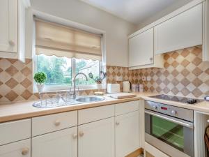 a kitchen with white cabinets and a sink and a window at Polly's Fold in Grassington +12 photos