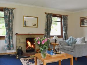 a living room with a fireplace and a couch at Bethany Cottage in Aberfoyle