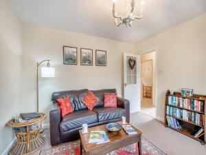 a living room with a leather couch and a table at Polly's Fold in Grassington