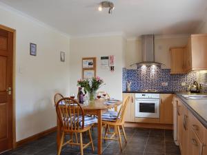 a kitchen with a wooden table and chairs and a kitchen with a stove at Bethany Cottage in Aberfoyle