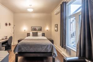 a bedroom with a bed and a large window at Petit Hôtel - Café Krieghoff in Quebec City